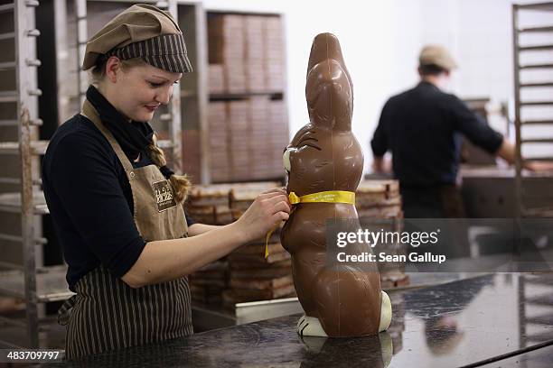 Employee Sandra Jaeckel, at the photographer's request, adjusts a ribbon around the neck of a giant chocolate Easter bunny at the production facility...