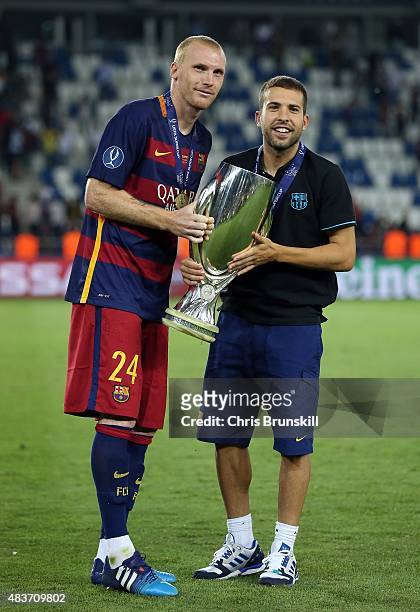 Jeremy Mathieu and Jordi Alba of Barcelona pose with the trophy following the UEFA Super Cup match between Barcelona and Sevilla FC at Dinamo Stadium...