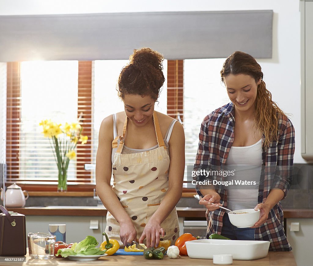 Friends cooking together in kitchen.