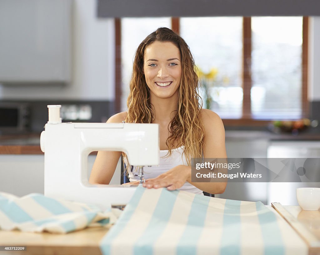 Woman using sewing machine at kitchen table.