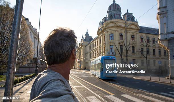 man looks down urban road to approaching cablecar - zagreb street stock pictures, royalty-free photos & images