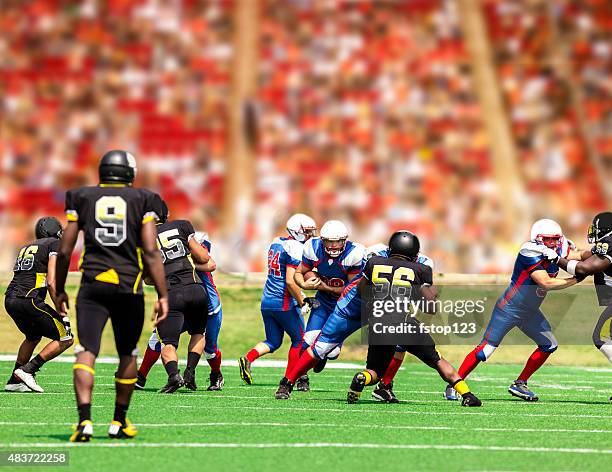 football team's running back carries ball. defenders. stadium fans. field. - offense sporting position stockfoto's en -beelden