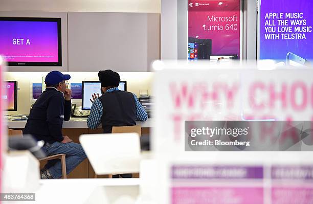 An employee speaks with a customer inside a Telstra Corp. Retail store in Melbourne, Australia, on Thursday, Aug. 13, 2015. Telstra posted profit...