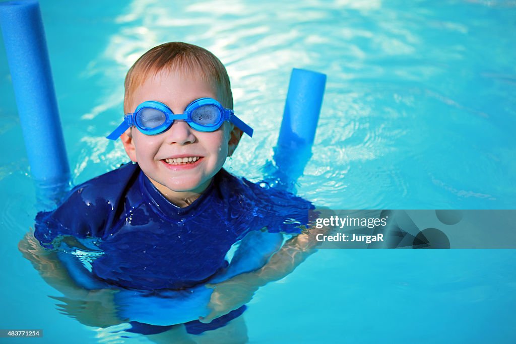 Child with Noodle Float and Swimming Goggles Learning to Swim