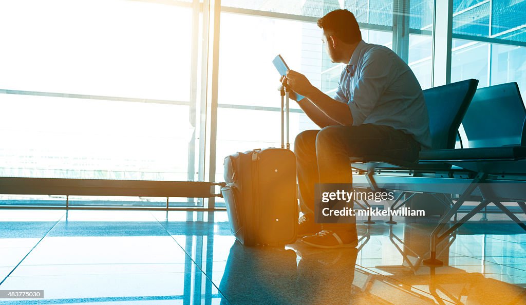 Man waits for plane at airport and looks for flight