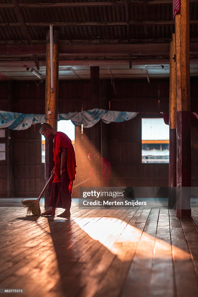 Buddhist monk sweeping monastery floor