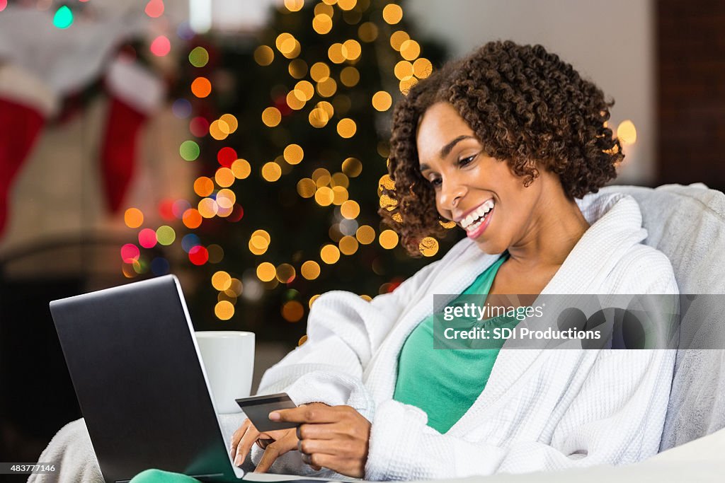 Woman using laptop and credit card to buy Christmas gifts