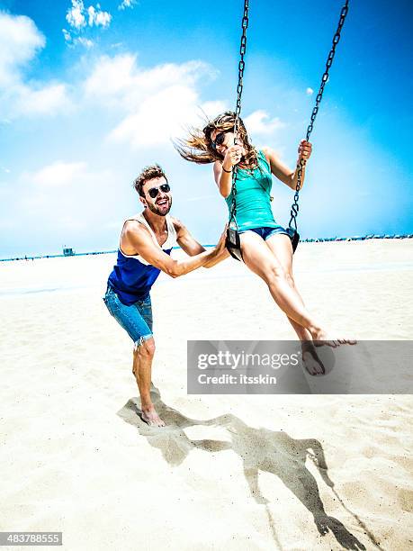 paar auf schaukel teetering la beach - junge frau strand sand springen stock-fotos und bilder