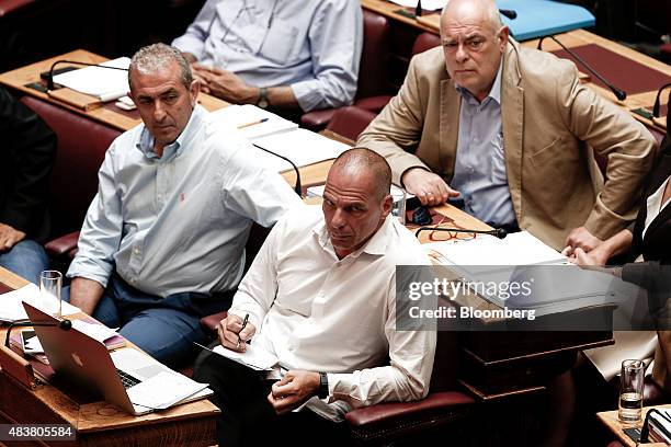 Yanis Varoufakis, former Greek finance minister, center, takes notes during a parliamentary session ahead of a vote by lawmakers on a bailout deal in...