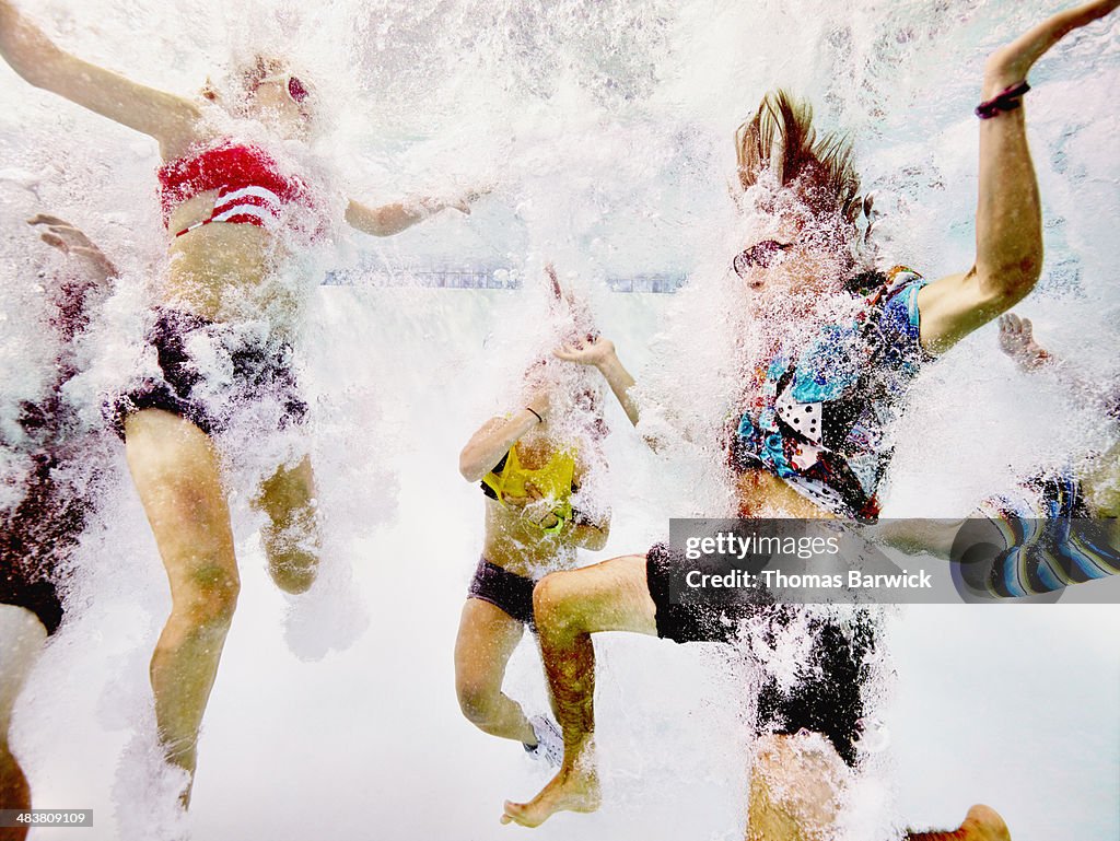 Group of young friends jumping into pool