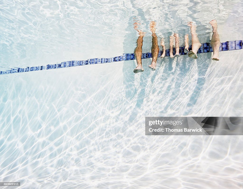 Family's feet hanging in swimming pool