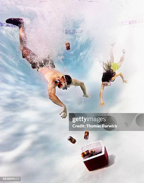 young couple diving underwater after cooler - blank can stockfoto's en -beelden