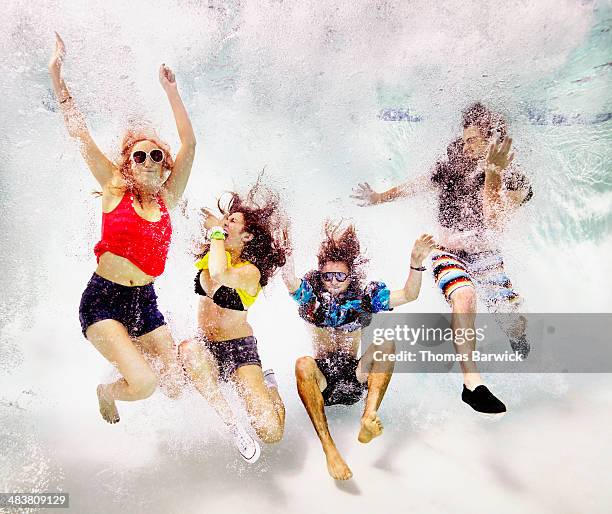 Group of young friends jumping into pool