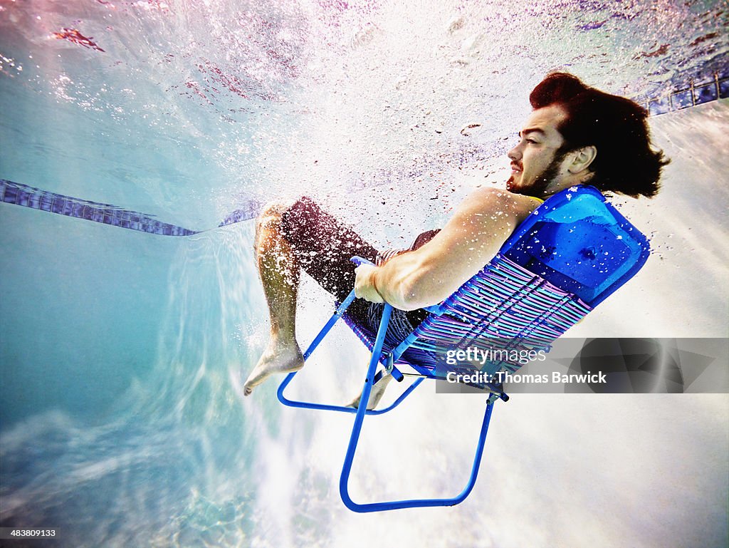 Man underwater sitting in chair underwater view