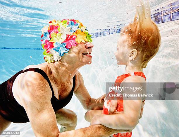 smiling grandmother and granddaughter underwater - two kids looking at each other stockfoto's en -beelden