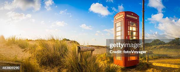 klassische britische rote telefon box in idyllischer sommer strand-dünen - telefonzelle stock-fotos und bilder