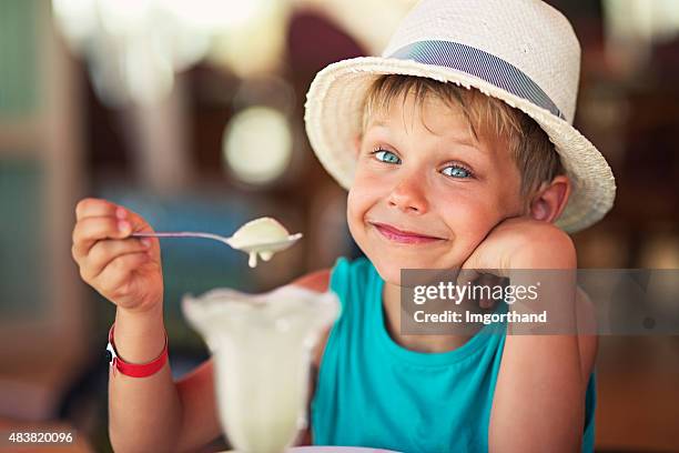 poco niño comiendo un helado en el restaurante - postres lacteos fotografías e imágenes de stock