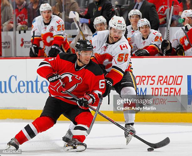 Andy Greene of the New Jersey Devils plays the puck while being stick checked by Ben Hanowski of the Calgary Flames during the game at the Prudential...