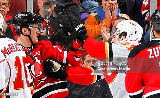 Kenny Agostino of the Calgary Flames and Eric Gelinas of the New Jersey Devils push and shove each other during the game at the Prudential Center on...