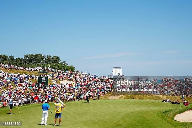 Fans watch the group of Rory McIlroy of Northern Ireland and Jordan Spieth and Zach Johnson of the United States on the first green during the first...