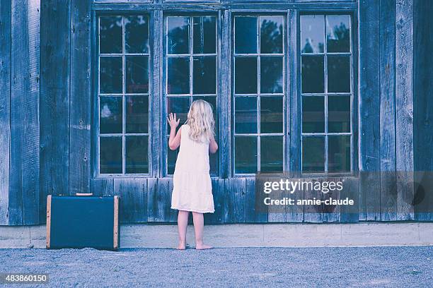 little girl looking in an abandoned cabin - orphan child stock pictures, royalty-free photos & images