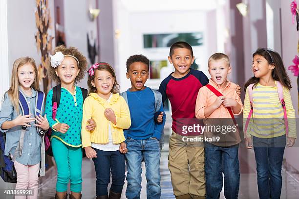 multiracial group of children in preschool hallway - kids in a row stock pictures, royalty-free photos & images