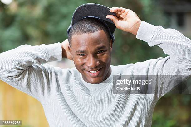 happy young black man wearing gray cap - man put on hat stock pictures, royalty-free photos & images