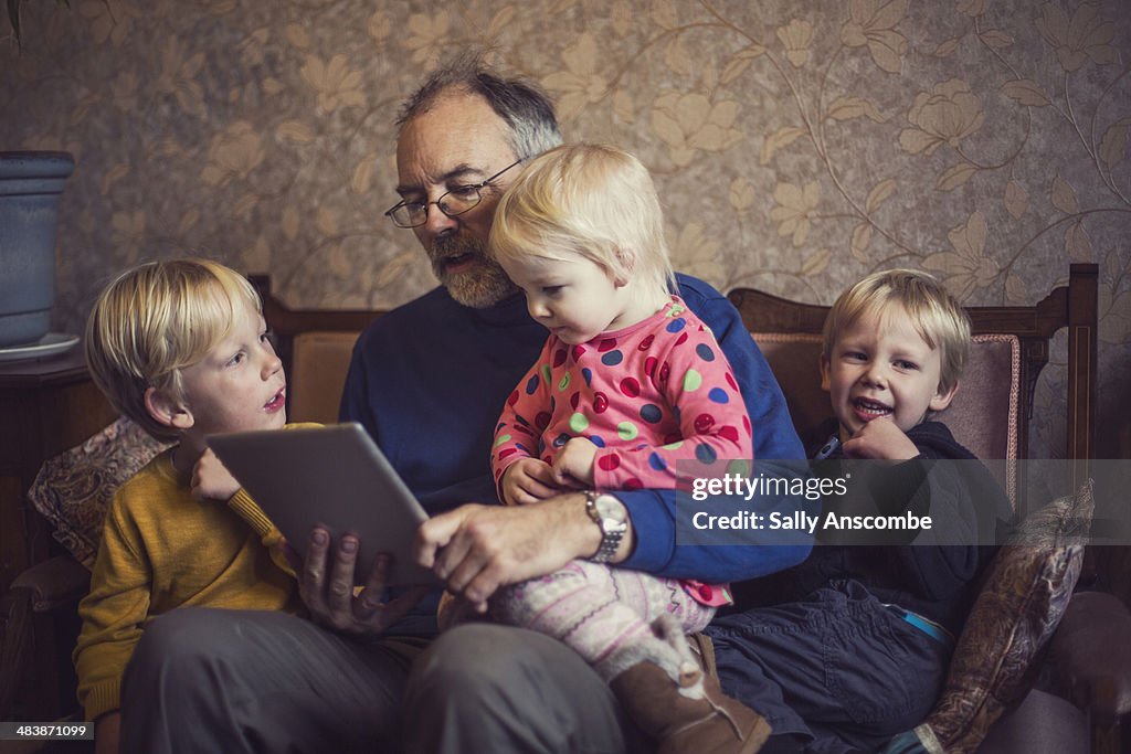 Children with their Grandpa using a tablet