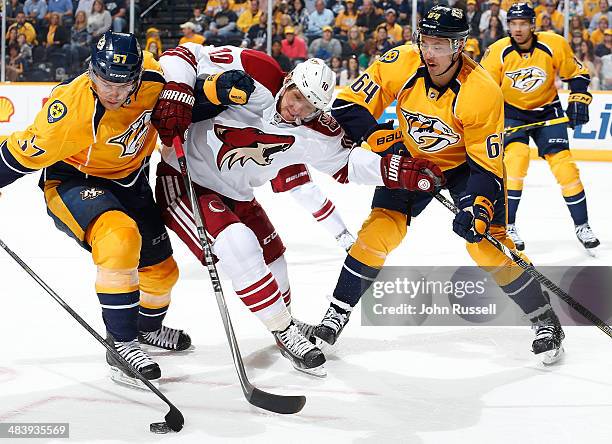 Martin Erat of the Phoenix Coyotes battles for the puck against Gabriel Bourque and Victor Bartley of the Nashville Predators during his 800th career...