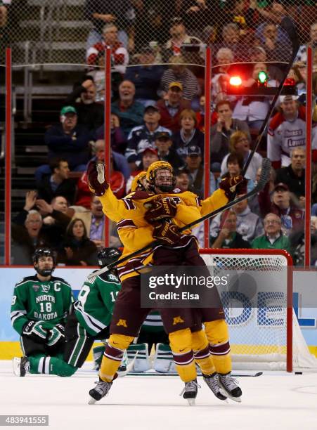 Justin Holl of the Minnesota Golden Gophers celebrates his game winning goal with teammate Seth Ambroz as Dillon Simpson of the North Dakota Fighting...