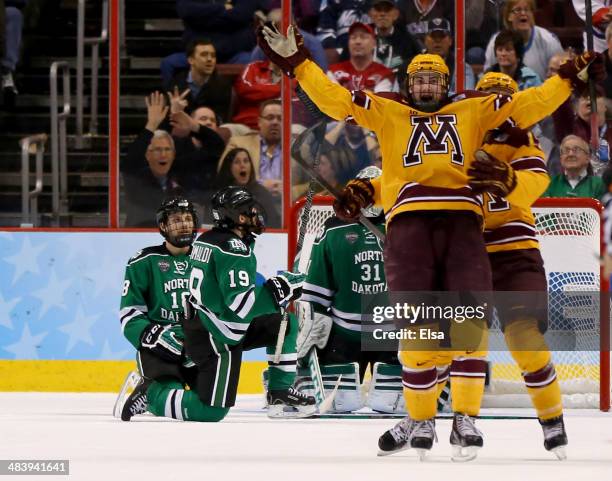 Justin Holl of the Minnesota Golden Gophers celebrates his game winning goal with teammate Seth Ambroz as Dillon Simpson and Rocco Grimaldi of the...