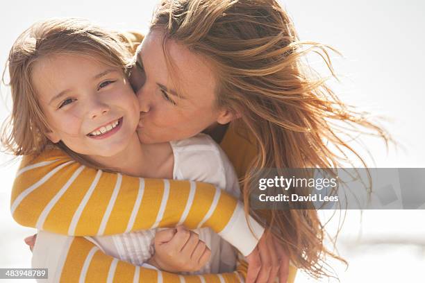 close up of mother kissing daughter at beach - kissing kids stockfoto's en -beelden