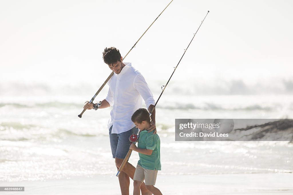 Father and son with fishing rods on beach