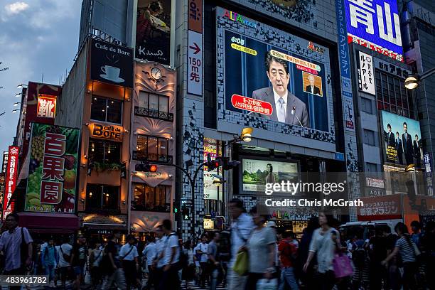 Pedestrians walk past a big screen showing a live broadcast of Japanese Prime Minister,Shinzo Abe as he delivers his WWII Anniversary Statement on...