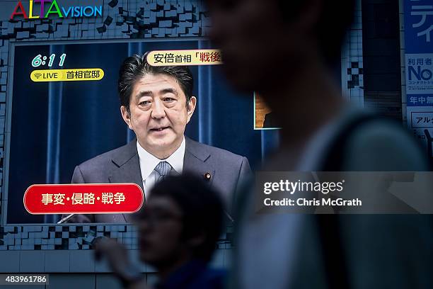 Pedestrians walk past a big screen showing a live broadcast of Japanese Prime Minister,Shinzo Abe as he delivers his WWII Anniversary Statement on...