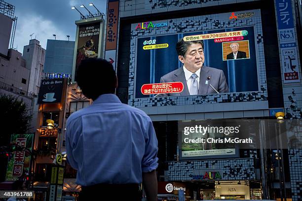 Man watches a big screen showing a live broadcast of Japanese Prime Minister, Shinzo Abe as he delivers his WWII Anniversary Statement on August 14,...