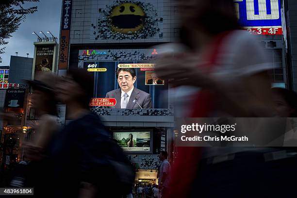 Pedestrians walk past a big screen showing a live broadcast of Japanese Prime Minister,Shinzo Abe as he delivers his WWII Anniversary Statement on...