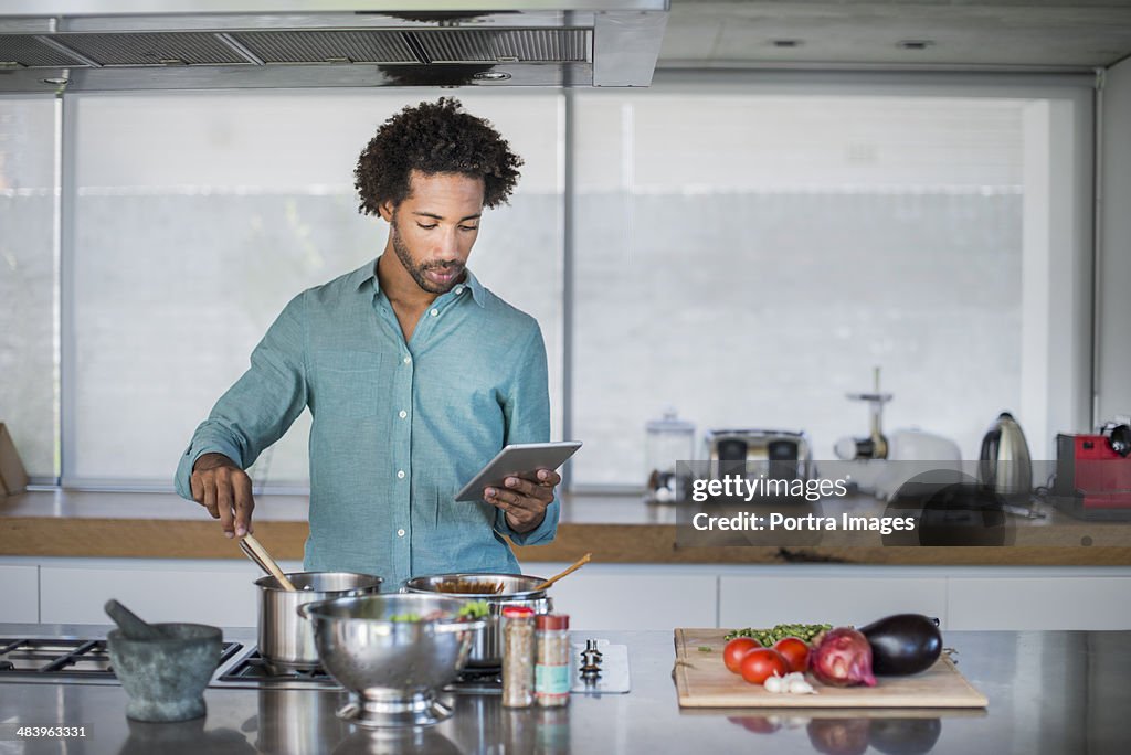 Man cooking reading a tablet while cooking