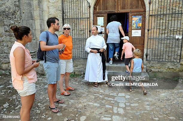 Father Guillaume Soury-Lavergne talks to visitors on August 12, 2015 outside the Benedictine abbey of Marcilhac-sur-Cele, in the Lot gorges, southern...