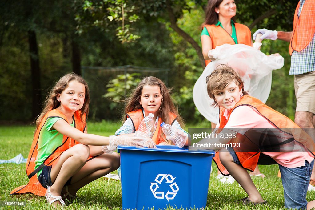 Volunteers: Family cleans up their community park. Recycling bin.