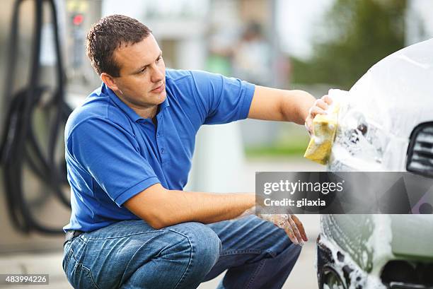 mid-aged man washing his car outdoors. - man washing car stock pictures, royalty-free photos & images