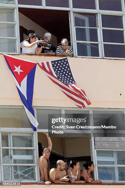 American and Cuban flags hang out of a window as people follow the flag-raising ceremony led by U.S. Secretary of State John Kerry, on August 14 in...