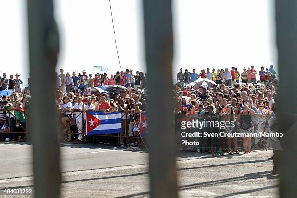 Cubans hold a Cuban flag outside the newly opened US embassy as they follow the flag-raising ceremony led by U.S. Secretary of State John Kerry, on...