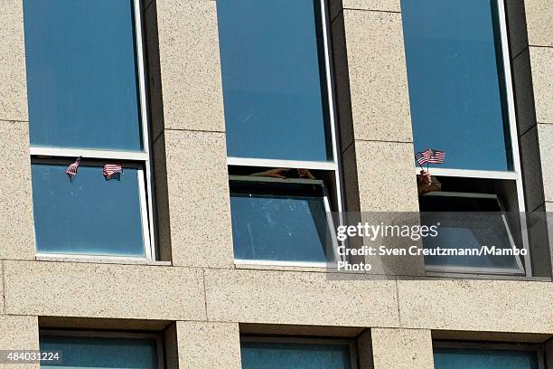 Employees of the newly opened US embassy in Cuba wave US flags, prior to the flag-raising ceremony led by U.S. Secretary of State John Kerry, on...