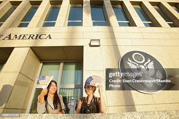 Participants use fans with the US flag to protect themselves from the sun at the newly opened US embassy in Cuba, prior to the flag-raising ceremony...