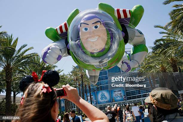 Attendees take photographs of Pixar movie Toy Story character Buzz Lightyear inflatable parade balloon outside during the Disney Legends Awards at...