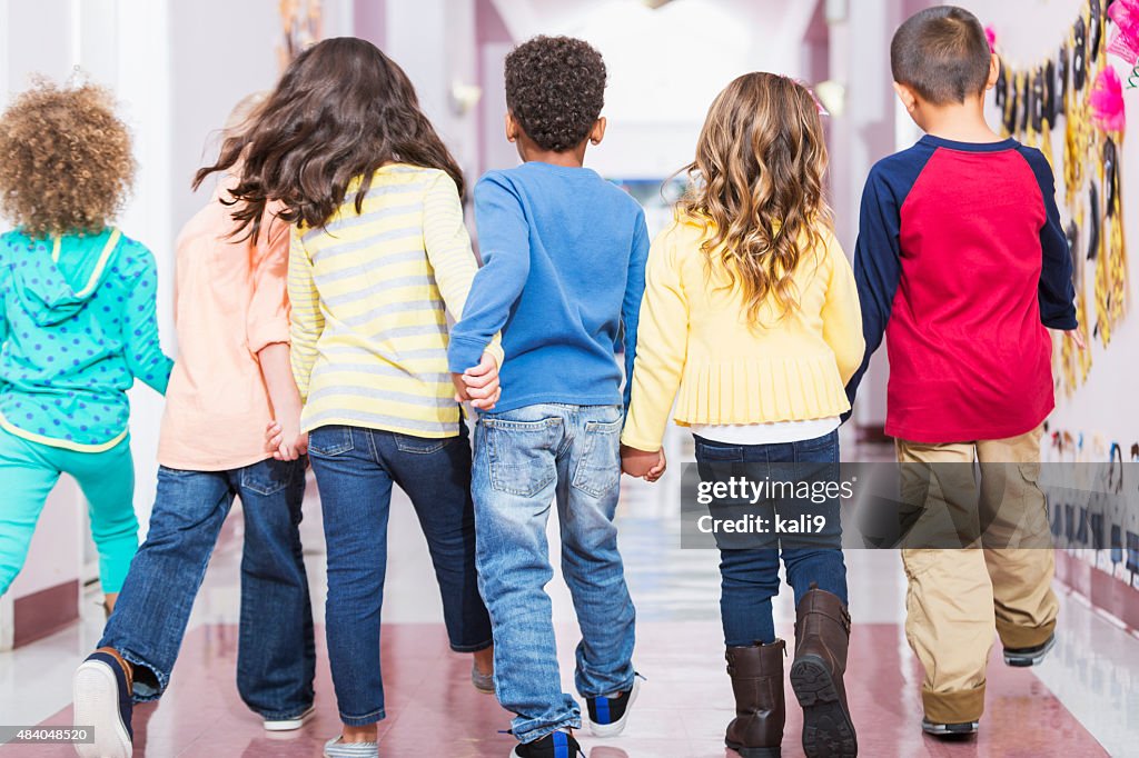 Rear view, group of preschoolers walking down hallway