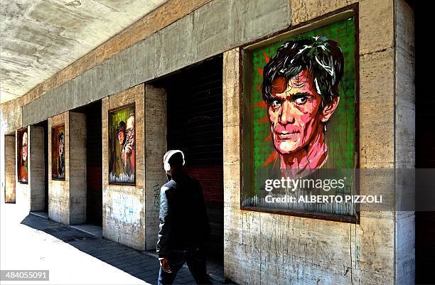 Man walks past a graffiti depicting Italian director Pier Paolo Pasolini by Italian artist David "Diavù" Vecchiato on the facade of the Cinema Impero...