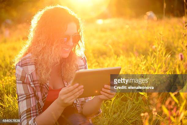 fille sur la nature avec une tablette pour ordinateur portable - fille lire gazon photos et images de collection