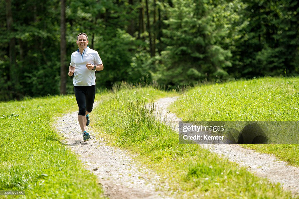 Sonriente hombre maduro corriendo en la naturaleza